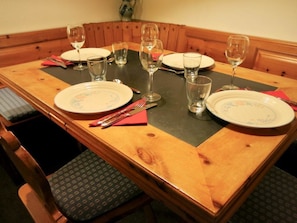 A dining table set with plates, glasses, and cutlery, surrounded by wooden chairs with cushioned seats. - Uf dr Egga 22 Appartement/Fewo, Dusche oder Bad, WC 2-Zimmerwohnung by Interhome (Davos)