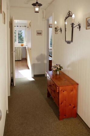 A hallway with a wooden bench, a wall-mounted light fixture, and a door leading to a room with a window. - Uf dr Egga 22 Appartement/Fewo, Dusche oder Bad, WC 2-Zimmerwohnung by Interhome (Davos)
