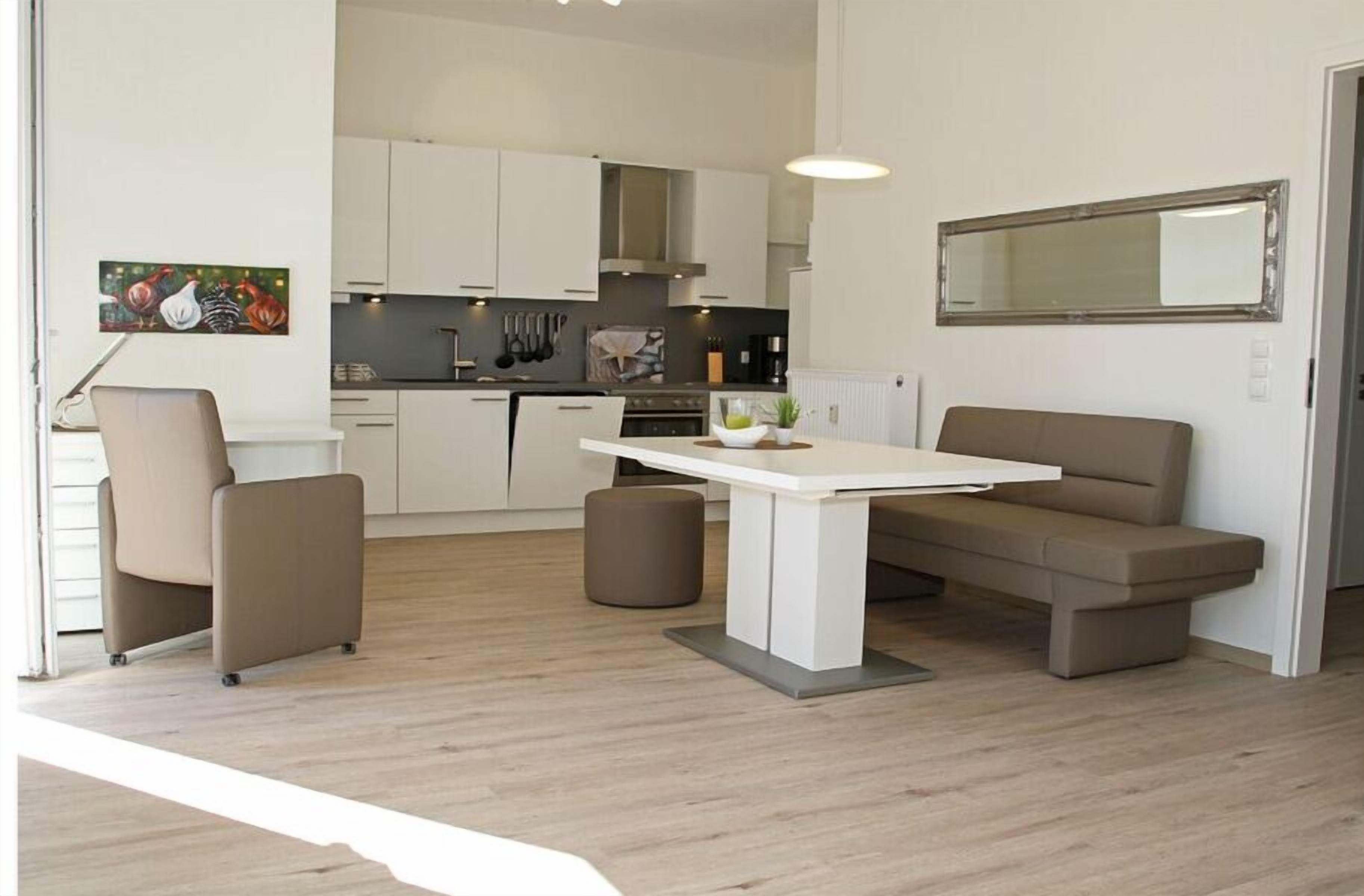 Une cuisine moderne avec des meubles blancs, une table à manger et un canapé.
