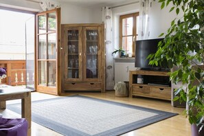 Ein Zimmer mit einem Holzkabinent, einem Fernseher und einer Pflanze.