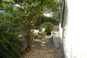 A patio area with a table and chairs, surrounded by greenery and a potted plant. - Holiday home with 1 bedroom (Julianadorp aan Zee)