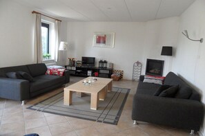 A living room with two sofas, a coffee table, a TV, and a framed picture on the wall. - Holiday home with 1 bedroom (Julianadorp aan Zee)