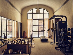 A gym with exercise equipment, a large mirror, and a window with curtains. - La Réserve Firenze (Firenze)