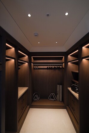 A walk-in closet with wooden shelving, a hanging rod, and a carpeted floor. - La Réserve Firenze (Firenze)