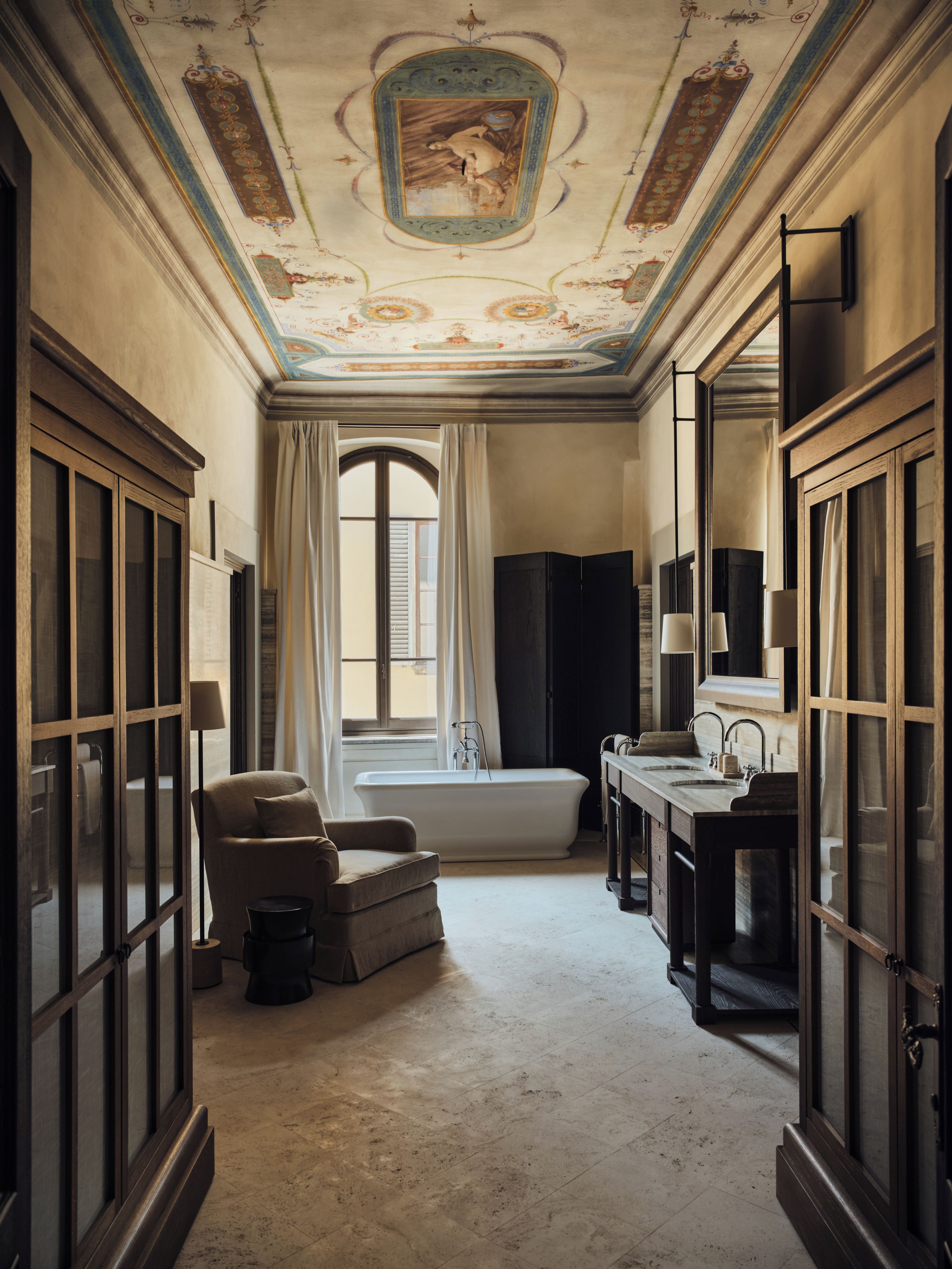 Une pièce avec une baignoire, une chaise, un bureau et des placards.