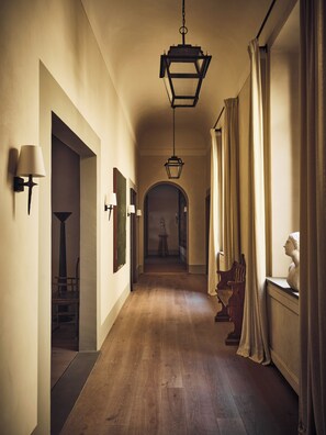 A hallway with wooden flooring, wall-mounted lamps, and a hanging lantern. - La Réserve Firenze (Firenze)