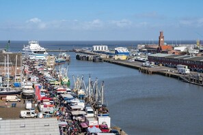 Een levendige haven met aangemeerde boten, een steiger die het water in reikt en fabrieksgebouwen op de achtergrond.
