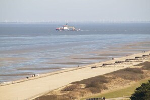 A coastal landscape with a sandy beach, a ship in the distance, and wind turbines in the background. - Luca Panorama Apt. 16, 1st floor (Cuxhaven\/Duhnen)
