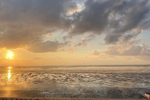 A beach with a sunset, clouds, and a calm sea. - Luca Panorama Apt. 16, 1st floor (Cuxhaven\/Duhnen)