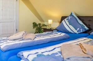 A hotel room with a bed, pillows, a nightstand, a lamp, and a plant. - Holiday apartment Trientje (Borkum)