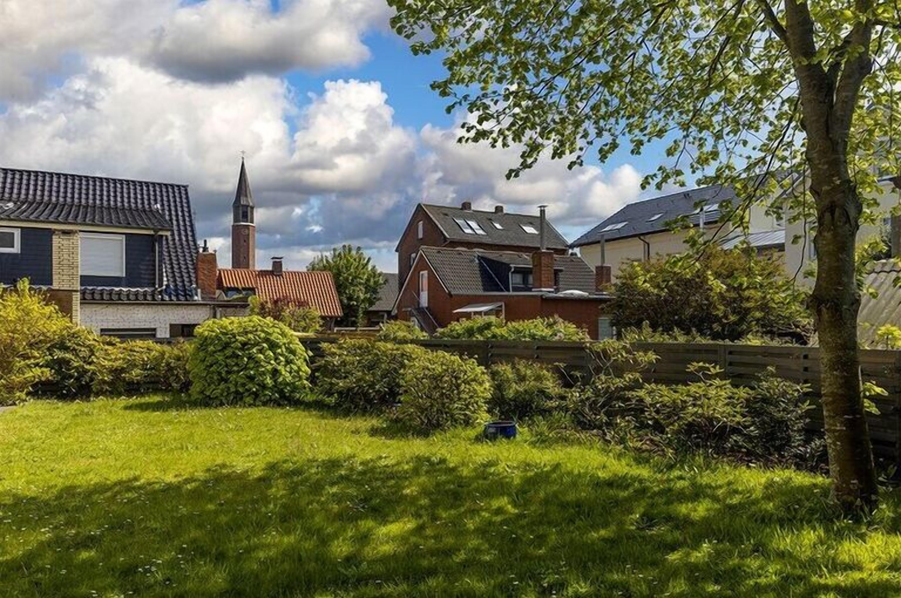 Ett bostadsområde med hus, en kyrka och en välskött gräsmatta.
