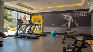 Une salle de sport équipée de tapis de course, d’un vélo d’appartement et de matériel de musculation.