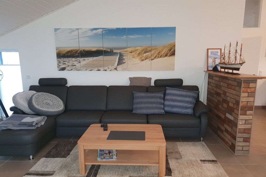 A modern living room with a large beach-themed wall art, a dark sofa, a coffee table, and a brick fireplace.