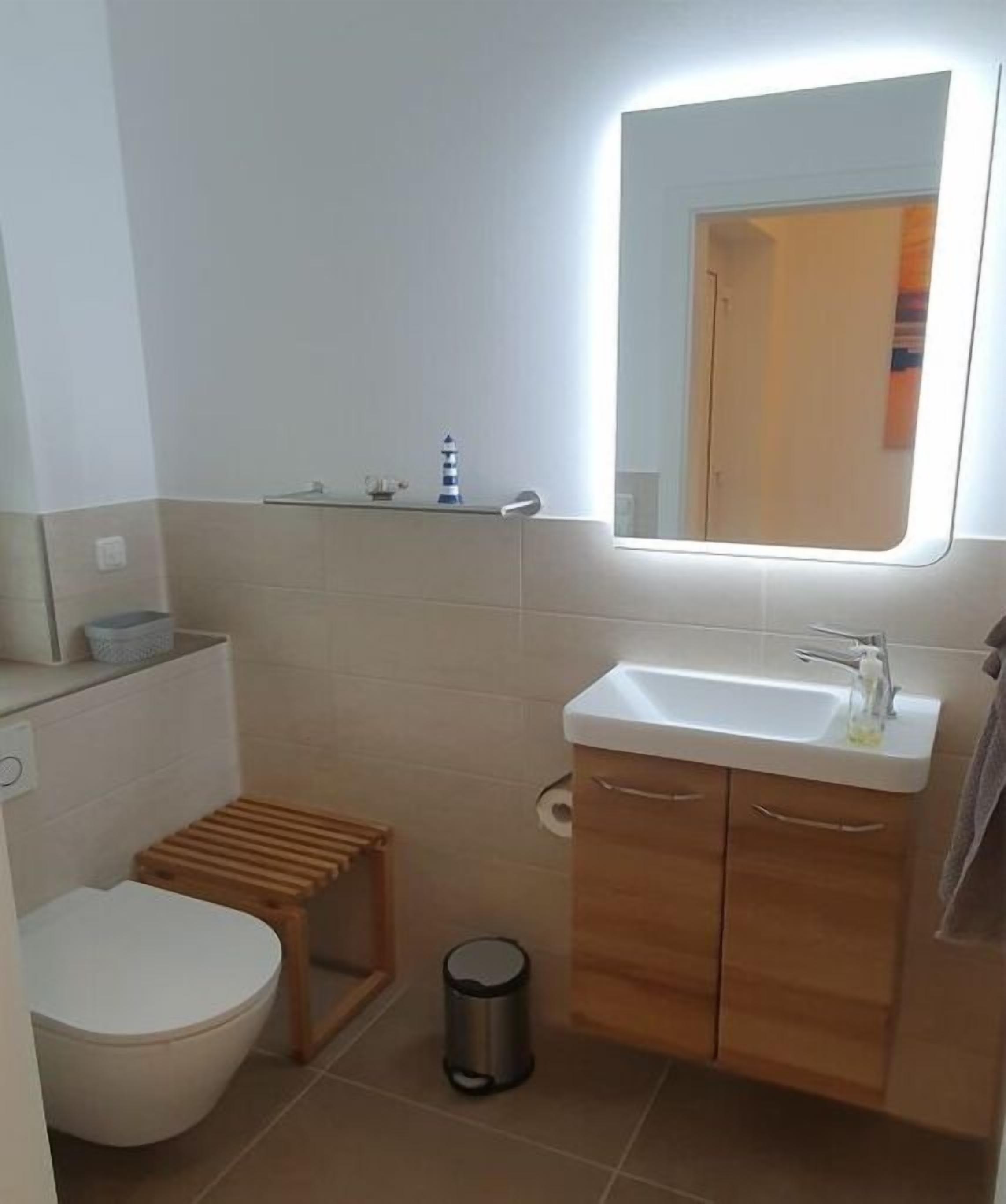 Ein Badezimmer mit Toilette, Waschbecken, Spiegel und einer kleinen Ablage für Pflegeprodukte.