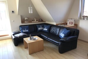 A modern living room with a sectional sofa, a coffee table, and a small side table with decorative items. - Holiday apartment with 2 bedrooms (Cuxhaven)