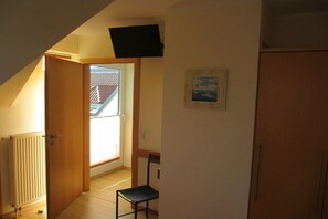 Une pièce avec un radiateur, une chaise, une porte donnant sur un balcon et un tableau accroché au mur.