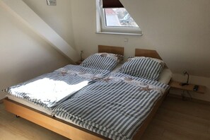 Un lit simple avec un cadre en bois, une literie à rayures et une petite table de chevet avec une lampe.