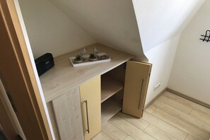 A small, enclosed room with a sloped ceiling, a built-in shelf with decorative items, and a wall-mounted hook. - Holiday apartment with 2 bedrooms (Cuxhaven)
