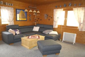 Una habitación acogedora con un sofá gris, una mesa de centro de madera y un radiador.