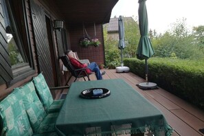 Un espacio de estar al aire libre cubierto con una mesa, sillas, una maceta colgante y una sombrilla.