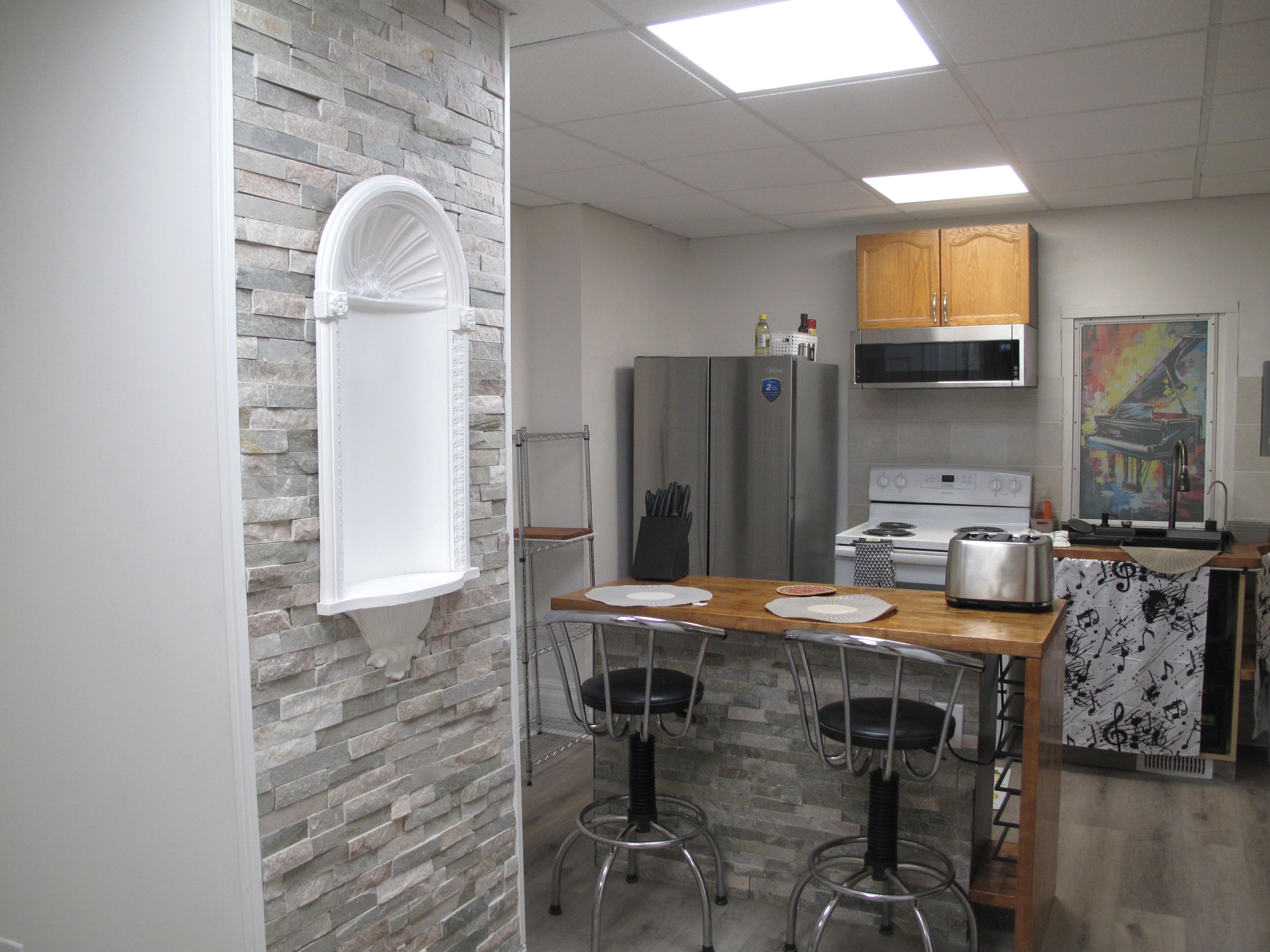 A kitchen with a stone backsplash, stainless steel appliances, and a wooden island with bar stools.