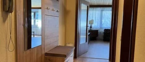 A hallway with wooden walls, a bench, a phone, and a door leading to another room.