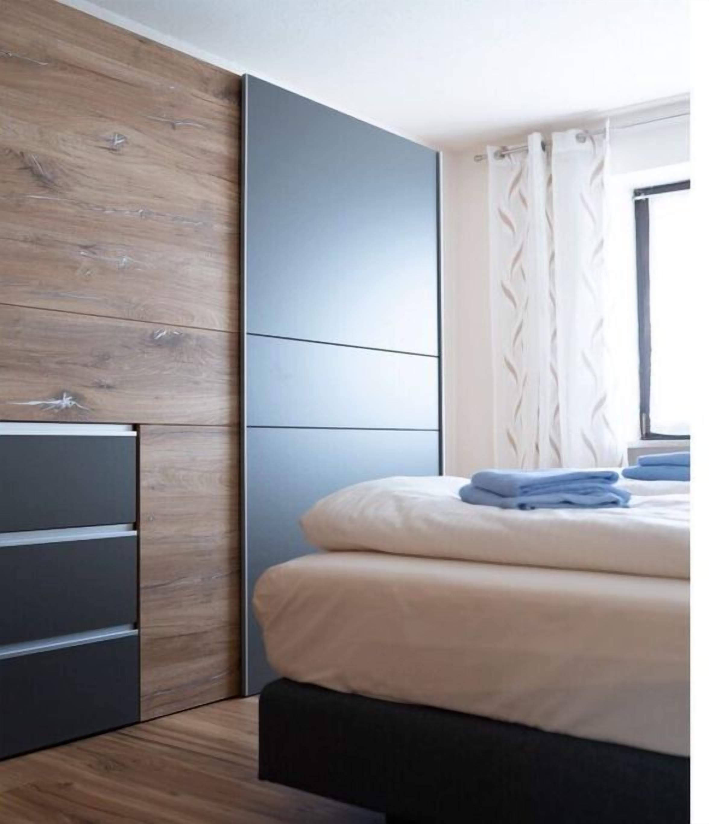 A bedroom with a bed, a wardrobe, and a window with curtains.