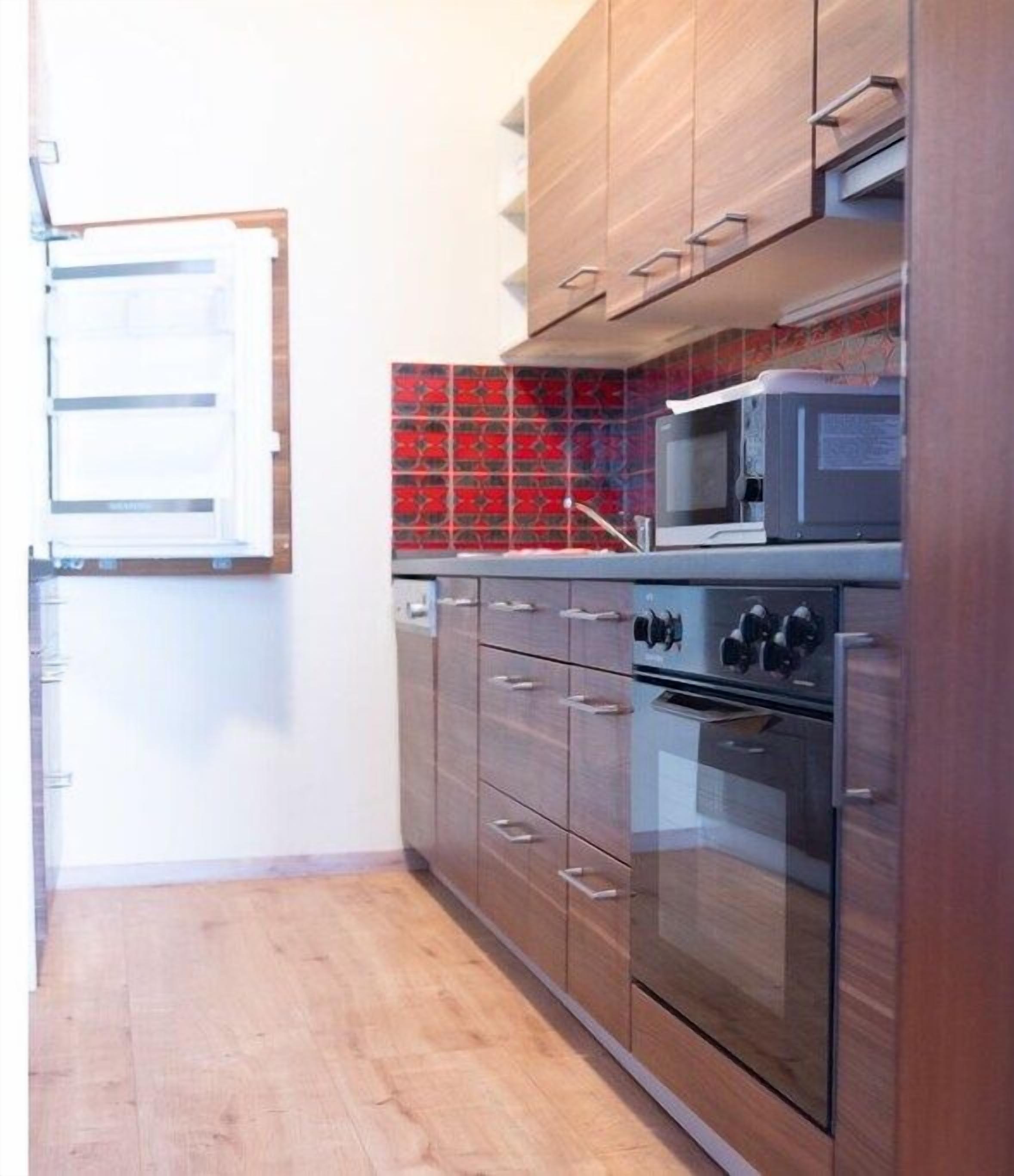 Una cocina con armarios de madera, microondas y horno doble.