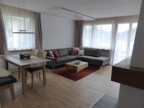 Ein modernes Wohnzimmer mit einer Couch, einem Esstisch und einem Couchtisch.