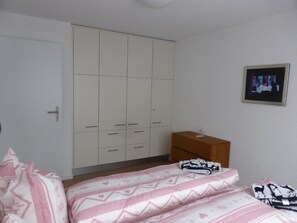 A bedroom with a bed, a wardrobe, a bedside table, and a framed picture on the wall. - Chesa Carnea 6 Appartement/Fewo, Dusche oder Bad, WC 3-Zimmerwohnung by Interhome (Klosters)