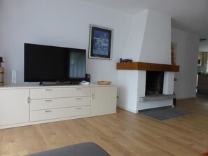 A living room with a flat-screen TV, a white cabinet, a fireplace, and a framed picture on the wall. - Chesa Carnea 6 Appartement/Fewo, Dusche oder Bad, WC 3-Zimmerwohnung by Interhome (Klosters)