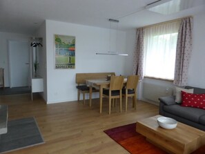 A modern living room with a grey sofa, a wooden coffee table, and a dining area with a wooden table and chairs. - Chesa Carnea 6 Appartement/Fewo, Dusche oder Bad, WC 3-Zimmerwohnung by Interhome (Klosters)