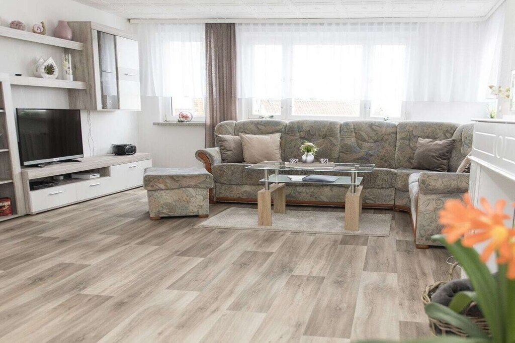 A modern living room with a sofa set, a coffee table, and a flat-screen TV.