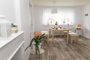 A dining area with a table, chairs, and a window with curtains. - Holiday home with 3 bedrooms (Blankenburg)