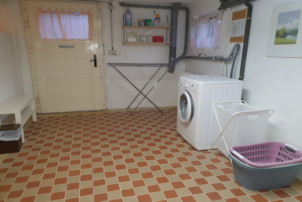 A laundry room with a washing machine, a drying rack, and a laundry basket.