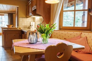A wooden dining table with a checkered tablecloth, a vase with flowers, and a candle. - Holiday apartment with 2 bedrooms (Ruhpolding)