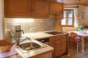 Eine Küche mit Holzausstattung, einem Spülbecken, einer Kaffeemaschine und einem Essbereich mit Tisch und Stühlen.