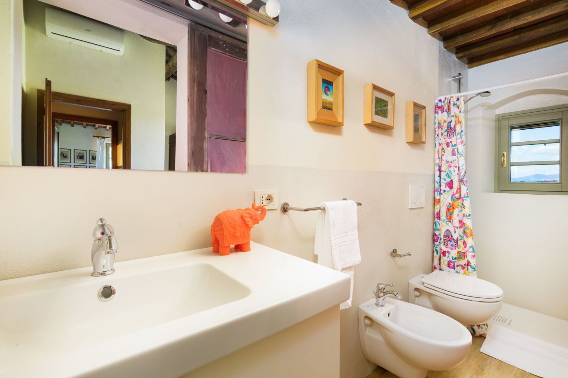 A bathroom with a white sink, a bidet, a toilet, and a shower curtain.
