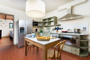 A modern kitchen with a dining table, chairs, and a variety of appliances. - Villa Bellaria, Private Pool, Bolgheri (Bolgheri)