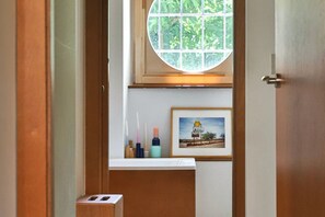 Een kamer met een raam, een lijst met een foto van een motelbord en een klein plankje met toiletartikelen.