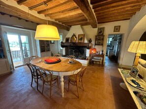 A dining area with a wooden table and chairs, a fireplace, and a view of the outdoors through a glass door. - Villa Stallina, Private Pool, Bolgheri (Bolgheri)