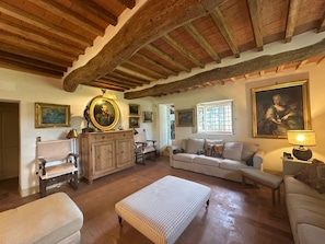 A traditional room with exposed wooden beams, a fireplace, a sofa set, and framed artwork on the walls. - Villa Stallina, Private Pool, Bolgheri (Bolgheri)