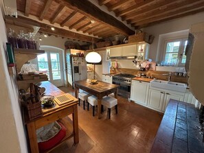 A kitchen with wooden beams, a central island, and white cabinetry. - Villa Stallina, Private Pool, Bolgheri (Bolgheri)