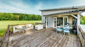 A wooden deck with outdoor furniture, a covered seating area, and a view of a green field. - Beautiful living at Elm (Schöppenstedt\/Eitzum)