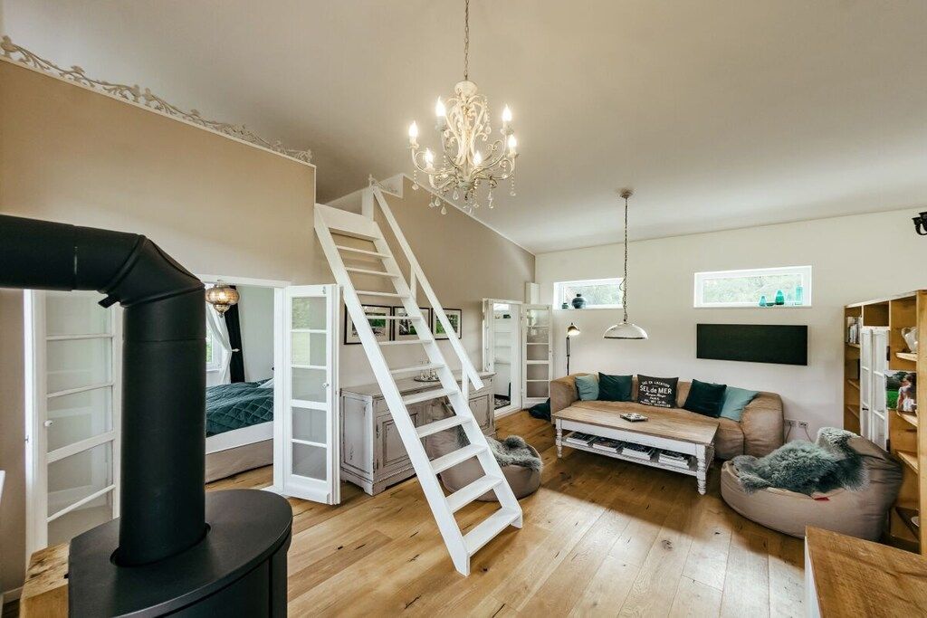 Un salon chaleureux avec une cheminée, un escalier, un canapé et une bibliothèque.