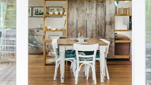 A dining area with a wooden table and white chairs, a black pendant light, and a rustic wooden backdrop. - Beautiful living at Elm (Schöppenstedt\/Eitzum)