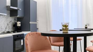 Une cuisine moderne avec des meubles gris, une cuisinière noire et une table ronde entourée de chaises.
