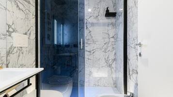 Ein modernes Badezimmer mit einer Duschkabine, einem weißen Waschbecken und einer Toilette.