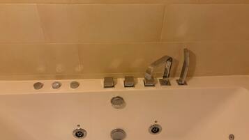 A bathtub with multiple faucets and a drain.