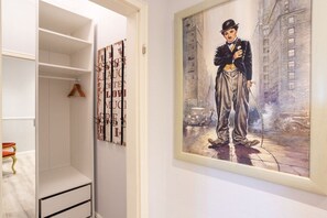 Ein Zimmer mit einem weißen Kleiderschrank, einem gerahmten Gemälde eines Mannes im Anzug und einem hölzernen Kleiderbügel im Schrank.
